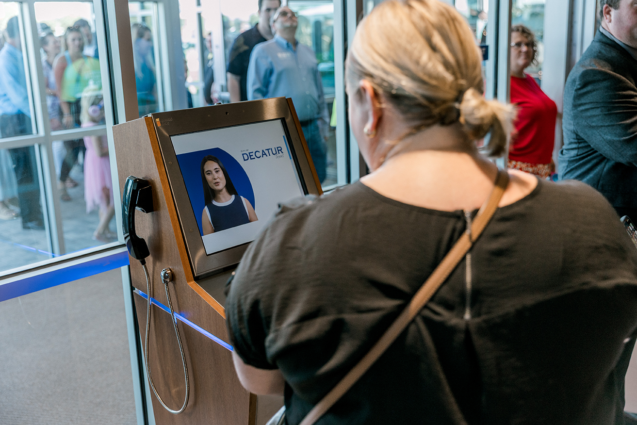 Woman watching instructional pop-up video on kiosk